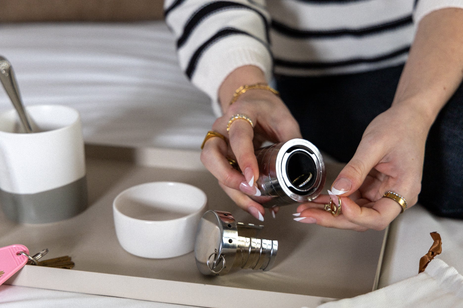 A woman with gold rings and French manicure opens her RockLock jewelry lockbox while enjoying a morning coffee in bed. Designed for security and convenience, RockLock keeps valuable jewelry safe, organized, and trackable at home or on the go.